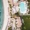 Aerial view of a luxury beach resort in the Caribbean with white sand, palm trees, and a turquoise ocean.