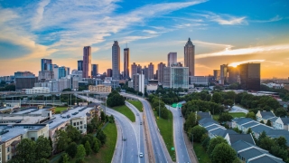 City skyline at sunset with highway in the foreground.