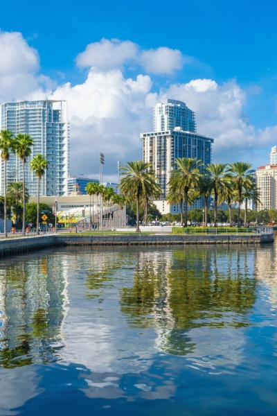 St. Petersburg, Florida waterfront with palm trees, tall modern buildings, and reflections in the water.