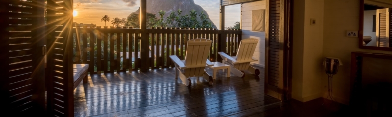 St. Lucia Sunset Balcony View – Wooden deck with chairs overlooking the Pitons and Caribbean Sea at sunset.