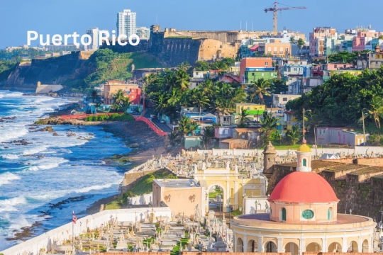 View of San Juan, Puerto Rico, with coastal fort, colorful houses, and dome of Santa María Magdalena de Pazzis Cemetery.