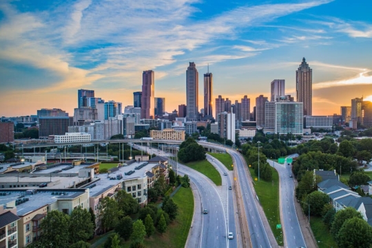 City skyline at sunset with highway in the foreground.