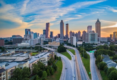 City skyline at sunset with highway in the foreground.