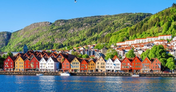 Colorful Bryggen houses line the Vågen harbor in Bergen, Norway, reflecting centuries of history against a backdrop of lush hills