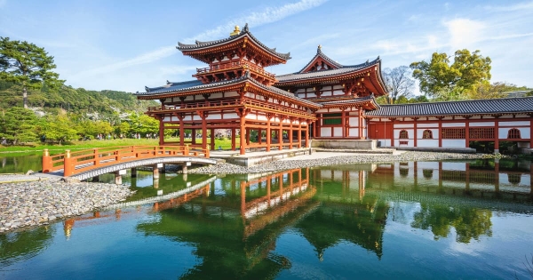 Byodo-in Temple in Uji, Kyoto, Japan with its red wooden architecture, arched bridge, and reflection in the pond.