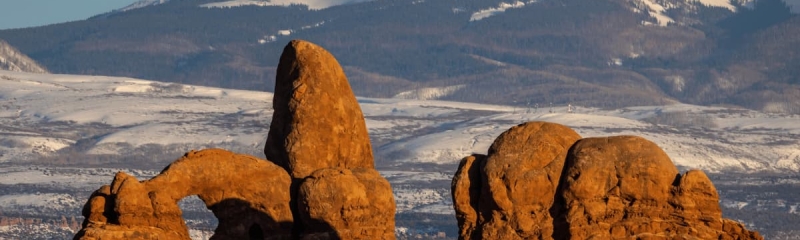 Turret Arch rock formation at Arches National Park, Utah, USA, with snow-capped La Sal Mountains in the background during winter.
