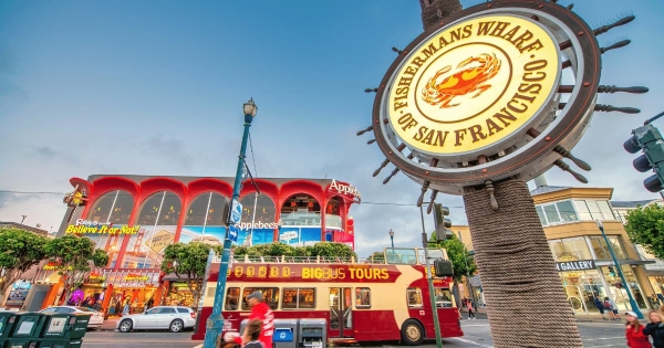 Fisherman’s Wharf sign with tour bus and shops in San Francisco, California