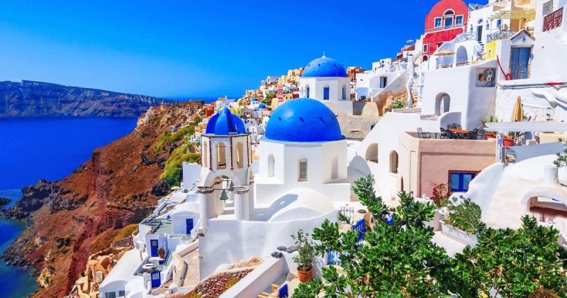 Blue domed church and whitewashed buildings overlooking the Aegean Sea in Oia, Santorini, Greece