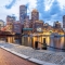 Boston Harbor waterfront at dusk with illuminated skyscrapers and boats in Massachusetts