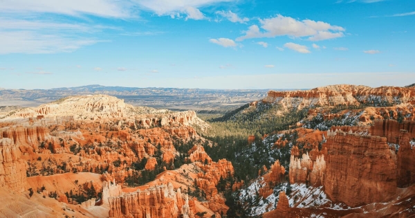 Scenic view of Bryce Canyon National Park in Utah with red rock hoodoos, cliffs, and forest under a bright blue sky