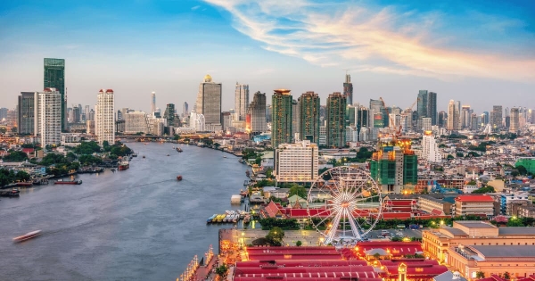Bangkok city skyline with Chao Phraya River, high-rise buildings, and Asiatique Ferris Wheel at sunset.