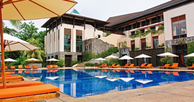 Luxury resort with outdoor pool, lounge chairs, and umbrellas.