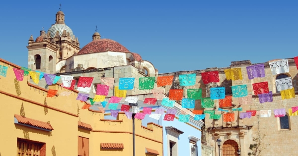 Colorful papel picado flags hanging in Oaxaca City with Santo Domingo Church in the background, Mexico